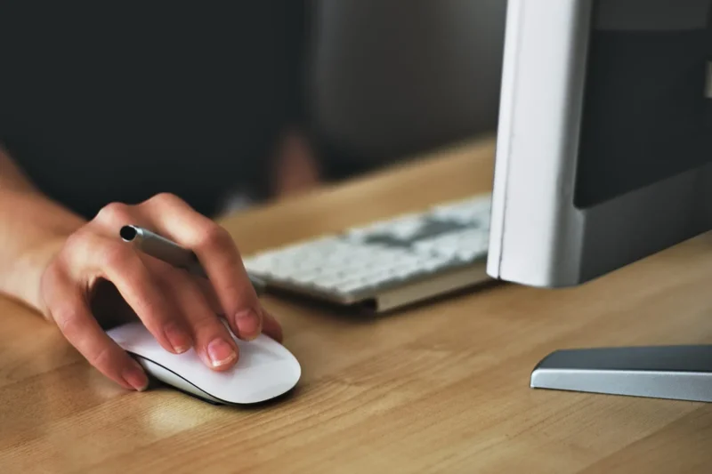 7 dicas para um portfolio eficiente. Mulher trabalhando em um computador em cima de uma mesa de madeira.