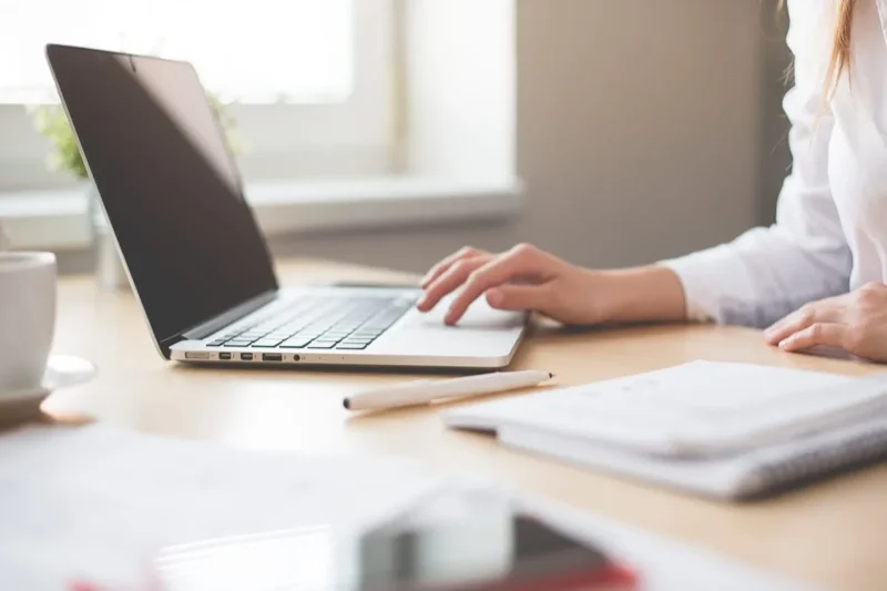 Como montar um portfolio sem ter clientes. Imagem mostrando uma pessoa trabalhando com um notebook que está em cima da mesa.